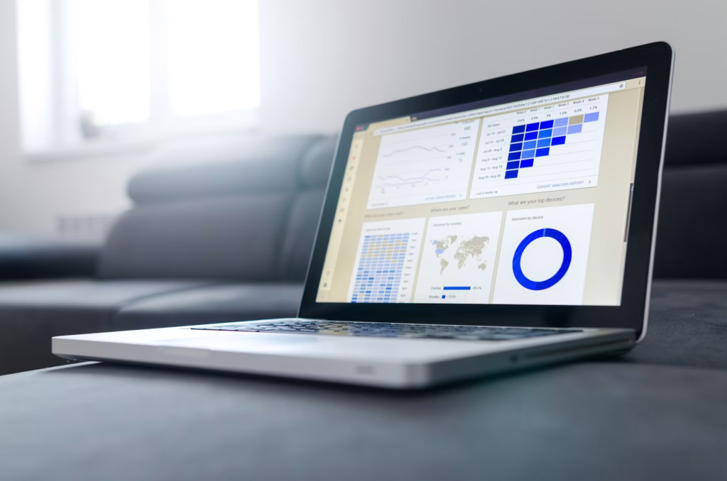 Laptop on a sofa showing a business dashboard of charts and a world map