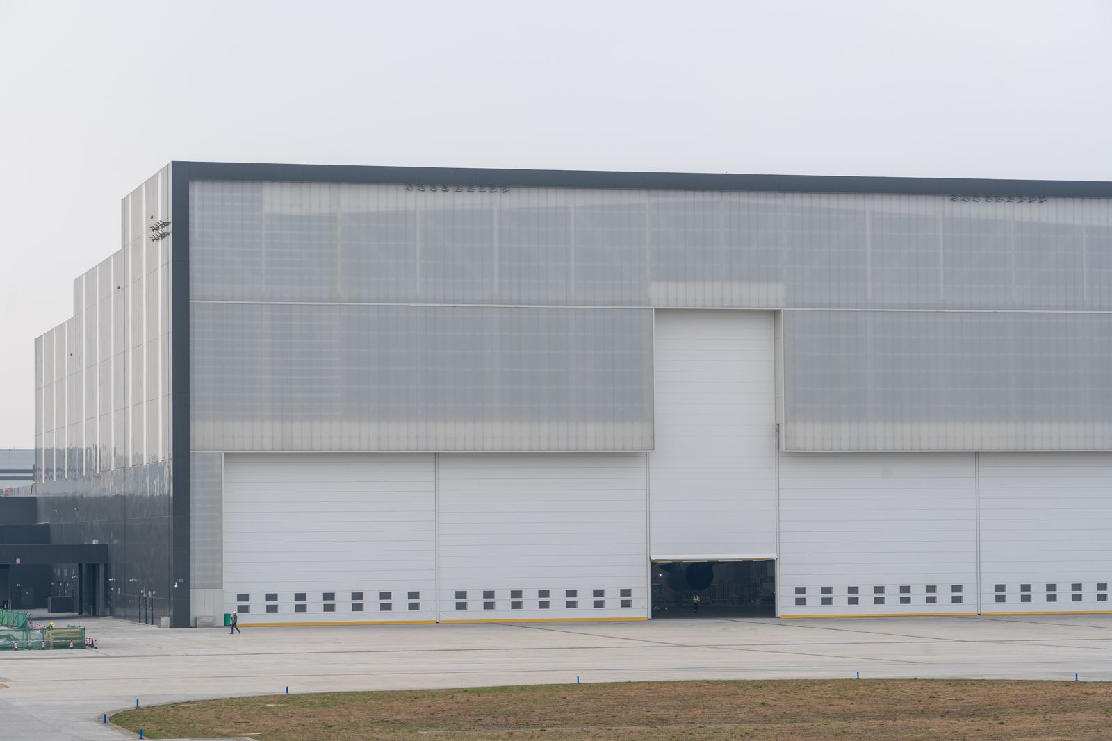 Large modern industrial warehouse with closed roller doors under a clear sky