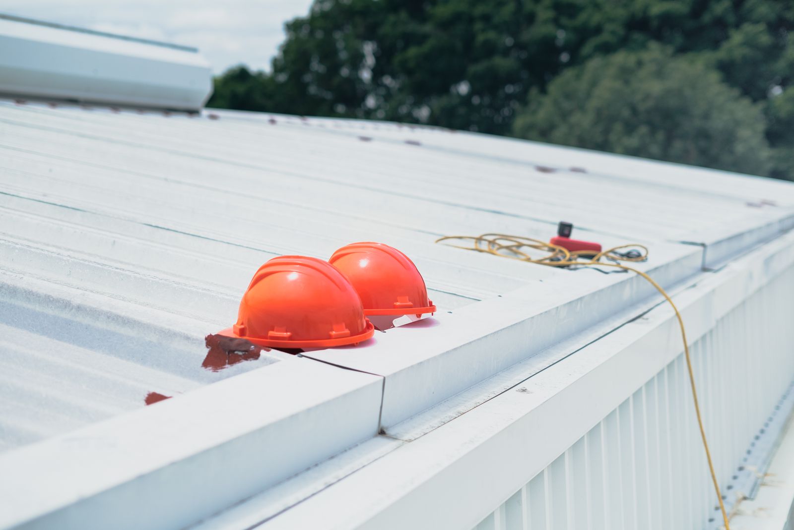 Red safety helmets and ear defenders lined up on a metal roof